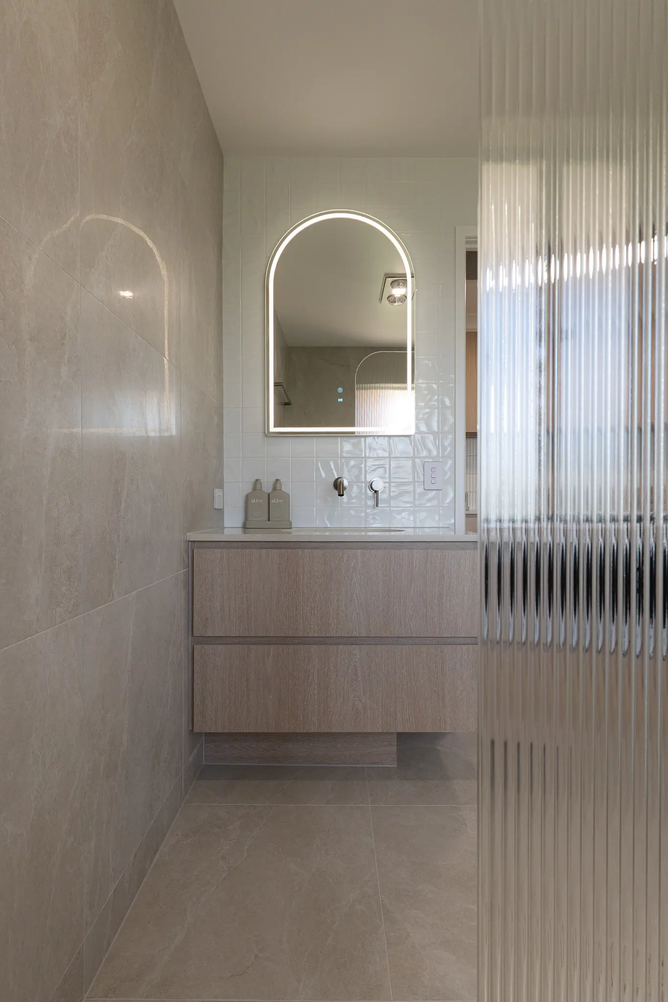 Bathroom with fluted glass shower screen and arched backlit mirror
