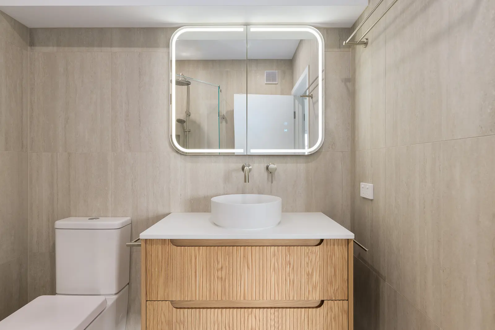 Renovated bathroom with timber vanity, round basin and backlit mirror